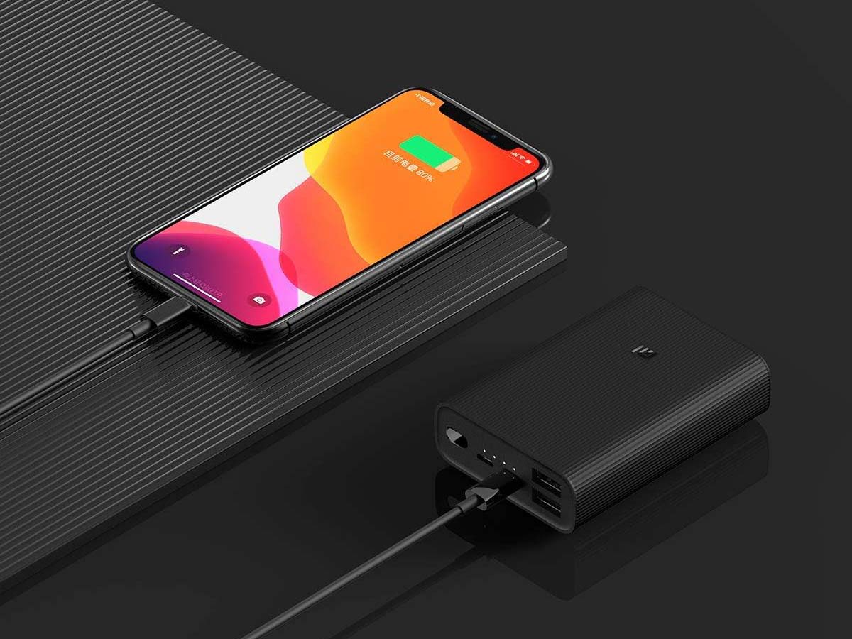 Smartphone charging from a black Xiaomi power bank with dual USB ports.